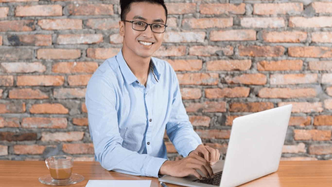 A male entrepreneur working on his laptop while smiling