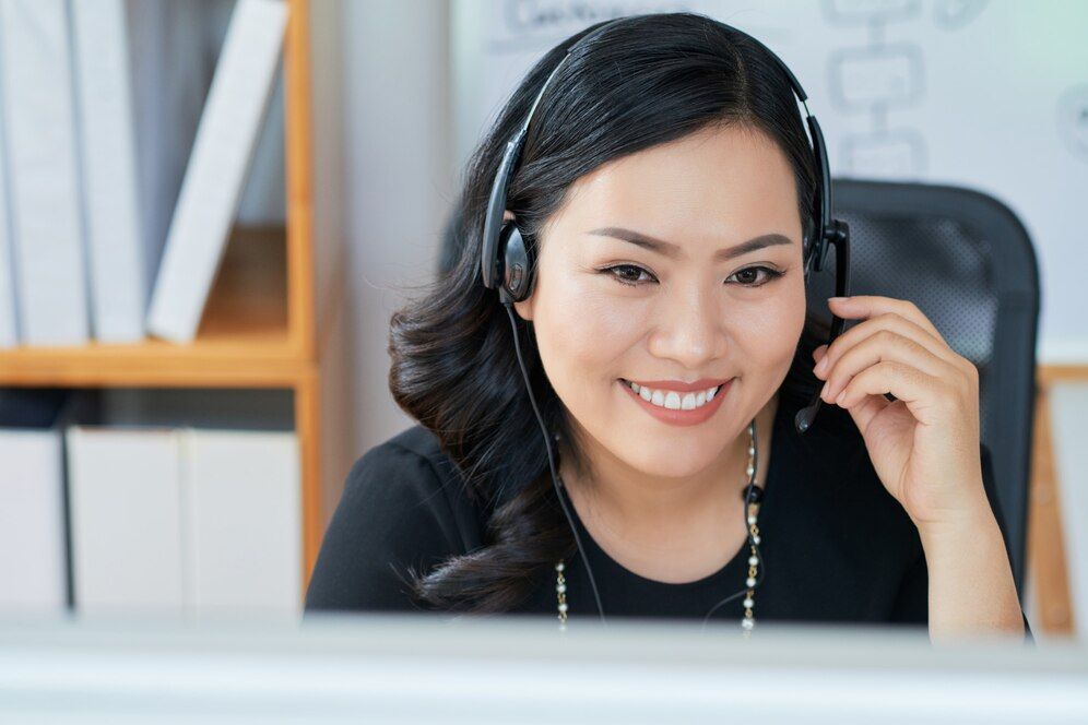 A call center agent wearing a headphone in front of a desktop computer
