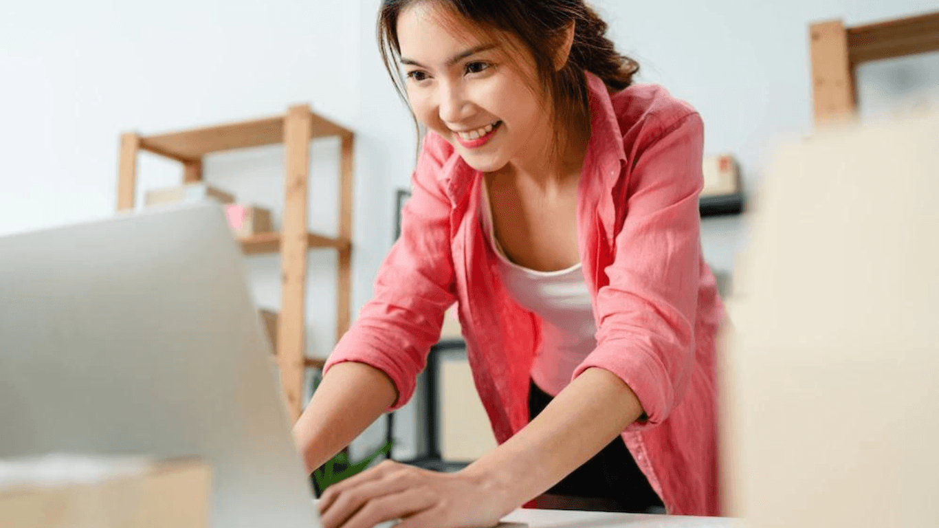 A happy female online retailer typing on her laptop