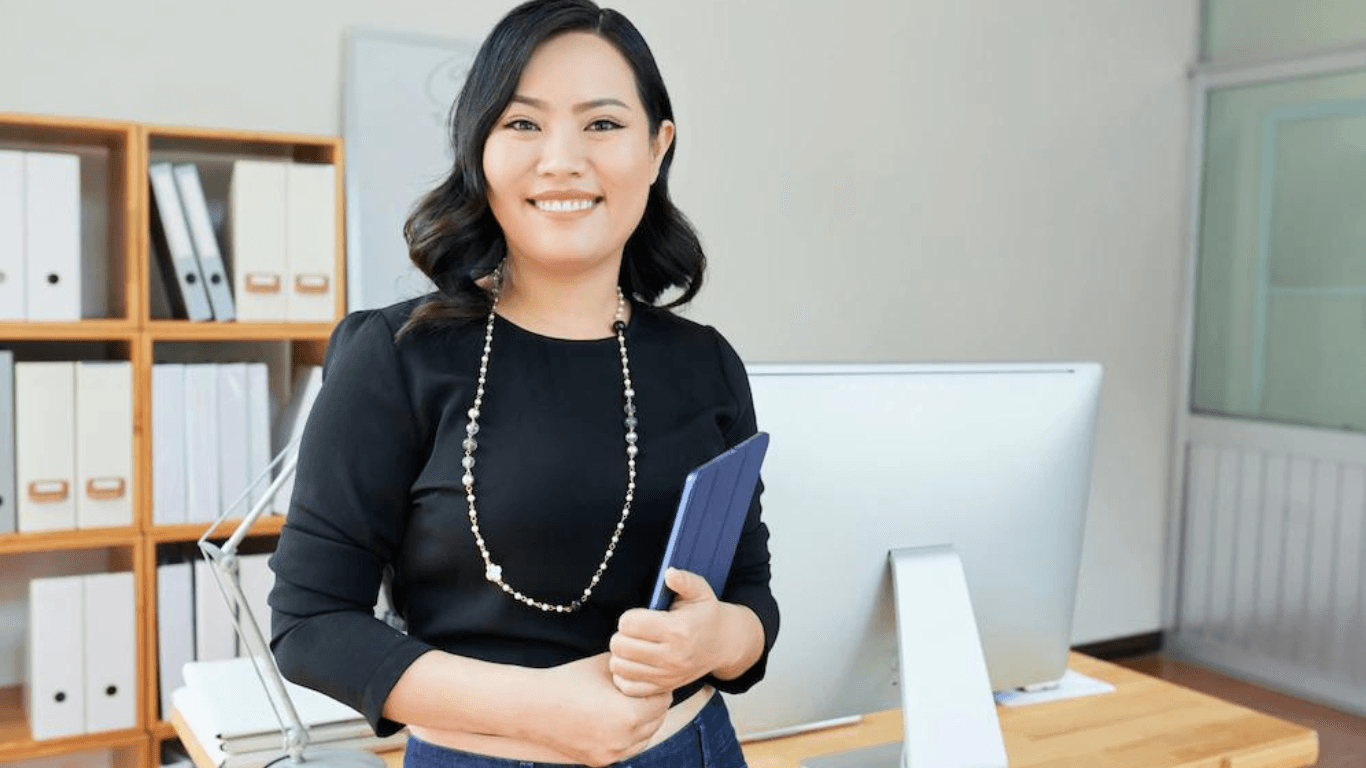 A businesswoman standing in front of her desk holding a tablet